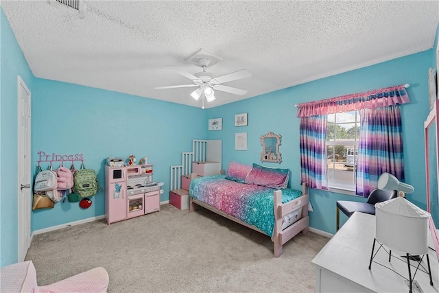 bedroom with ceiling fan, carpet floors, and a textured ceiling