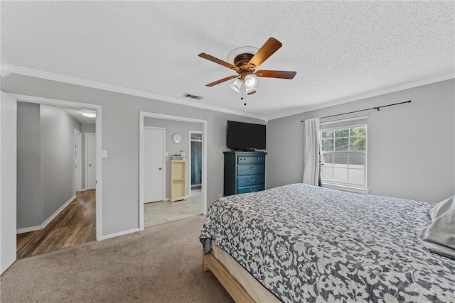 carpeted bedroom with a textured ceiling, ensuite bath, ceiling fan, and ornamental molding