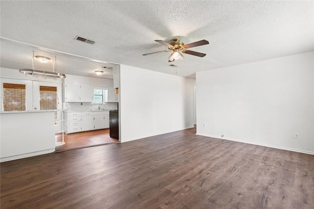 unfurnished living room featuring a textured ceiling, ceiling fan, and dark wood-type flooring