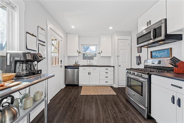 kitchen featuring sink, backsplash, stainless steel appliances, white cabinets, and dark hardwood / wood-style flooring