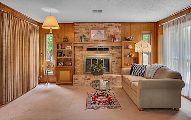 living room featuring wood walls, a fireplace, light carpet, and a textured ceiling