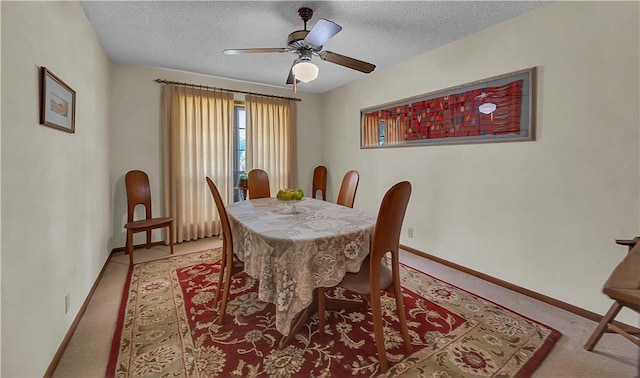 dining space with ceiling fan, light colored carpet, and a textured ceiling