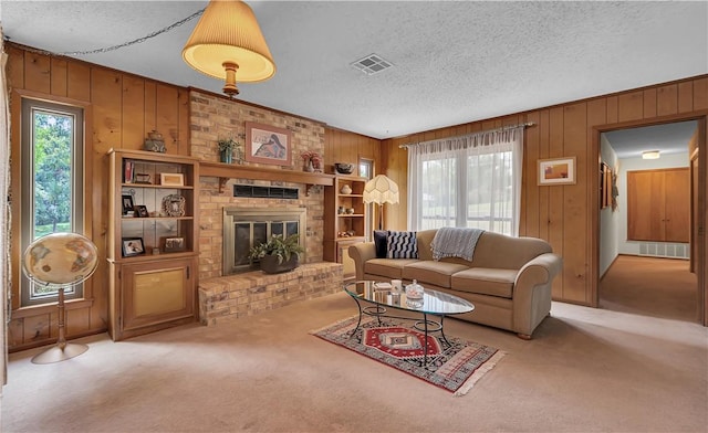 living room with a textured ceiling, light colored carpet, a brick fireplace, and wooden walls