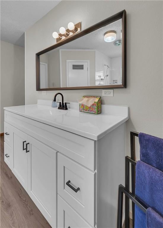 bathroom with hardwood / wood-style floors, vanity, and a textured ceiling