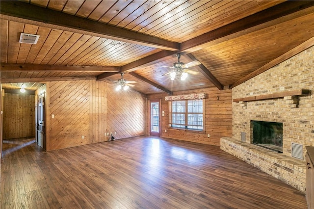 unfurnished living room featuring wood walls, wood ceiling, lofted ceiling with beams, a brick fireplace, and dark hardwood / wood-style flooring