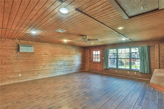 spare room featuring dark wood-type flooring, ceiling fan, a wall mounted AC, wooden ceiling, and wood walls