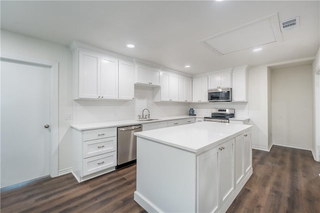 kitchen featuring stainless steel appliances, dark wood-type flooring, sink, a center island, and white cabinetry