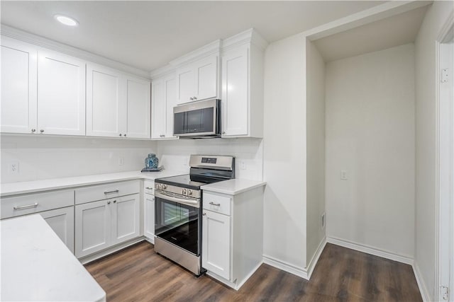 kitchen with appliances with stainless steel finishes, dark hardwood / wood-style floors, white cabinetry, and tasteful backsplash