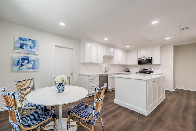 kitchen featuring a center island, sink, dark wood-type flooring, stainless steel appliances, and white cabinets