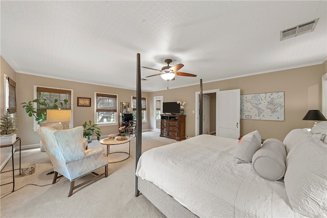 carpeted bedroom featuring ceiling fan, ornamental molding, and a textured ceiling