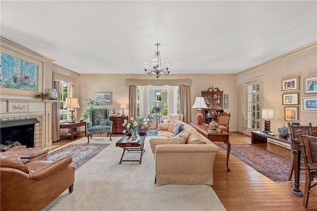 living room with a notable chandelier, a fireplace, light wood-type flooring, and crown molding