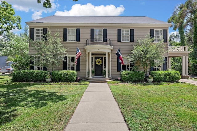 colonial-style house with a balcony and a front lawn