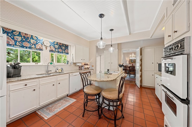 kitchen with a center island, white appliances, white cabinets, sink, and decorative light fixtures