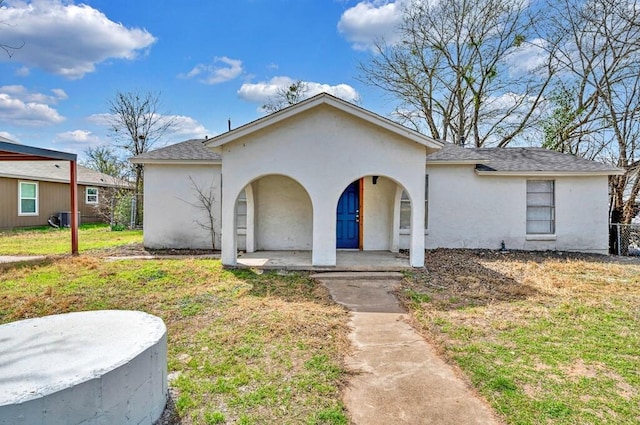 view of front of property with stucco siding, a porch, a front yard, and a shingled roof