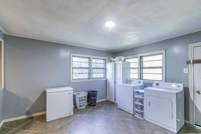 laundry room featuring crown molding, washer and clothes dryer, dark tile patterned floors, and a textured ceiling