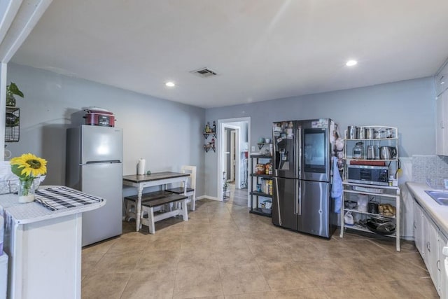 kitchen featuring stainless steel fridge, white cabinets, and light tile patterned flooring