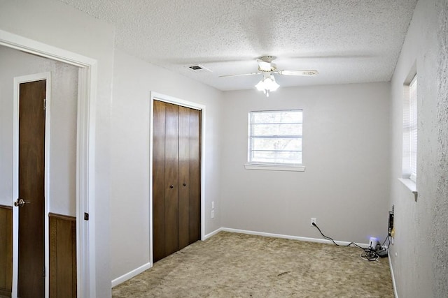 unfurnished bedroom featuring carpet, ceiling fan, a textured ceiling, and a closet