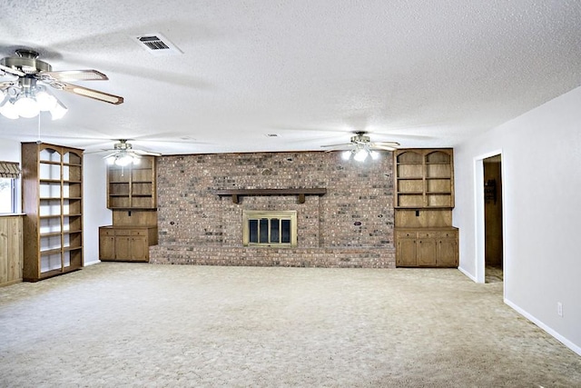 unfurnished living room featuring carpet flooring, built in shelves, a fireplace, and a textured ceiling