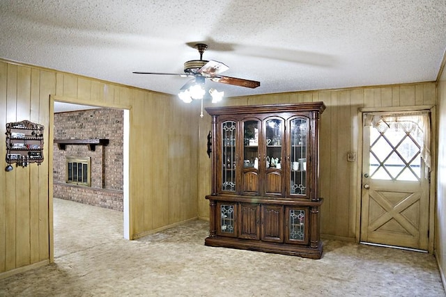 interior space featuring a textured ceiling, ceiling fan, and wooden walls