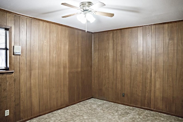 unfurnished room with carpet, ceiling fan, and wood walls