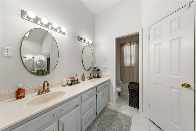 full bathroom featuring marble finish floor, double vanity, a sink, and toilet