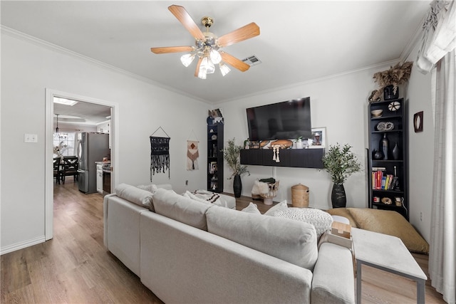 living room with a ceiling fan, ornamental molding, and wood finished floors