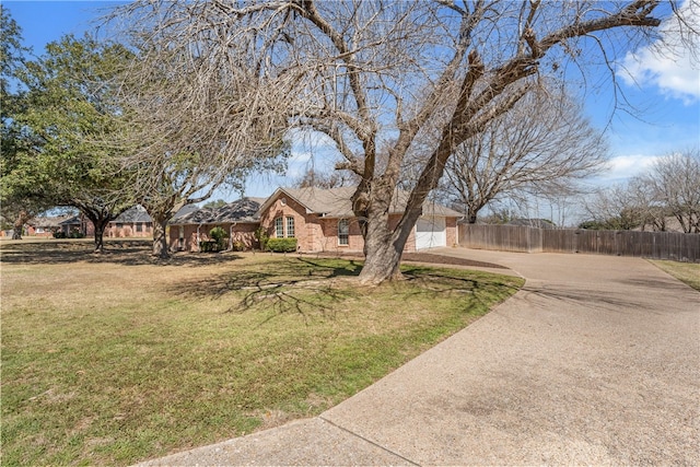 view of front of house featuring concrete driveway, brick siding, a front lawn, and fence