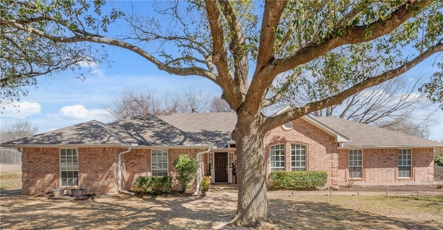 ranch-style house featuring brick siding and roof with shingles