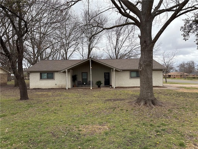 view of front of home with brick siding, roof with shingles, and a front lawn