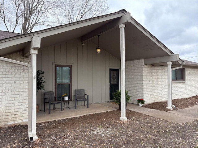 entrance to property featuring brick siding and roof with shingles