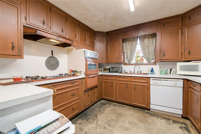 kitchen with a textured ceiling, stainless steel appliances, and sink