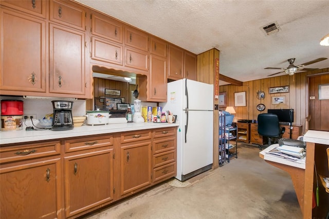 kitchen featuring a textured ceiling, white refrigerator, ceiling fan, and wood walls