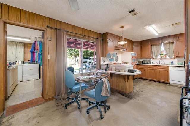 kitchen featuring wood walls, white dishwasher, sink, a textured ceiling, and decorative light fixtures