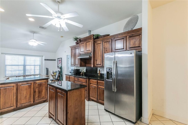 kitchen with appliances with stainless steel finishes, a kitchen island, lofted ceiling, and light tile patterned flooring