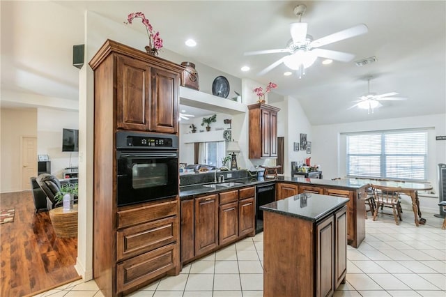 kitchen featuring kitchen peninsula, sink, black appliances, lofted ceiling, and light tile patterned flooring