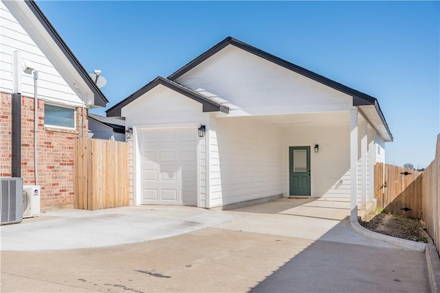 rear view of house featuring central AC unit and a garage