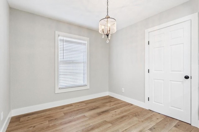 spare room featuring a notable chandelier and light hardwood / wood-style floors