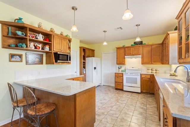 kitchen with a breakfast bar, white appliances, sink, decorative light fixtures, and kitchen peninsula