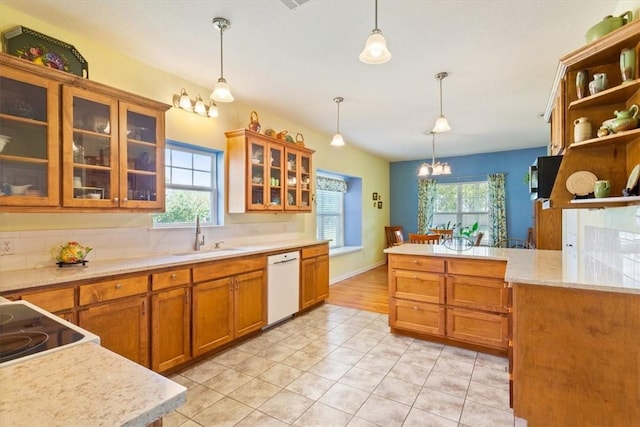 kitchen with white dishwasher, sink, light tile patterned floors, an inviting chandelier, and hanging light fixtures