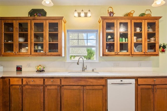 kitchen featuring decorative backsplash, white dishwasher, light stone counters, and sink