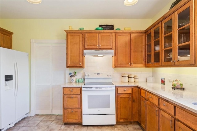 kitchen with light stone countertops, white appliances, light tile patterned floors, and tasteful backsplash