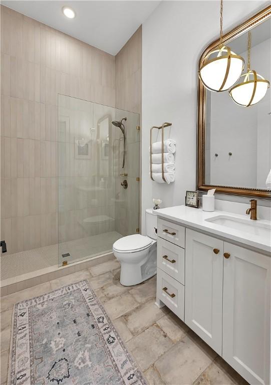 bathroom featuring vanity, toilet, and tiled shower