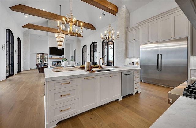 kitchen with white cabinetry, stainless steel appliances, sink, and hanging light fixtures