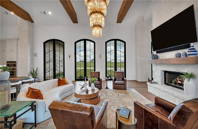 living room featuring a high end fireplace, beam ceiling, hardwood / wood-style floors, and a high ceiling