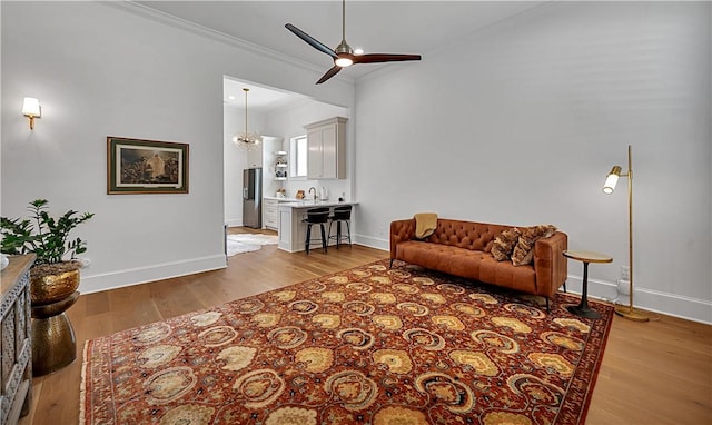 living room featuring crown molding, sink, ceiling fan with notable chandelier, and light hardwood / wood-style floors