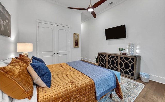 bedroom with hardwood / wood-style flooring, crown molding, ceiling fan, and a closet