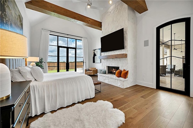 bedroom with hardwood / wood-style flooring, access to exterior, and beamed ceiling