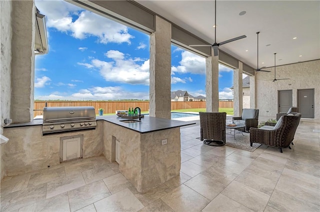 view of patio featuring ceiling fan, area for grilling, exterior kitchen, and sink