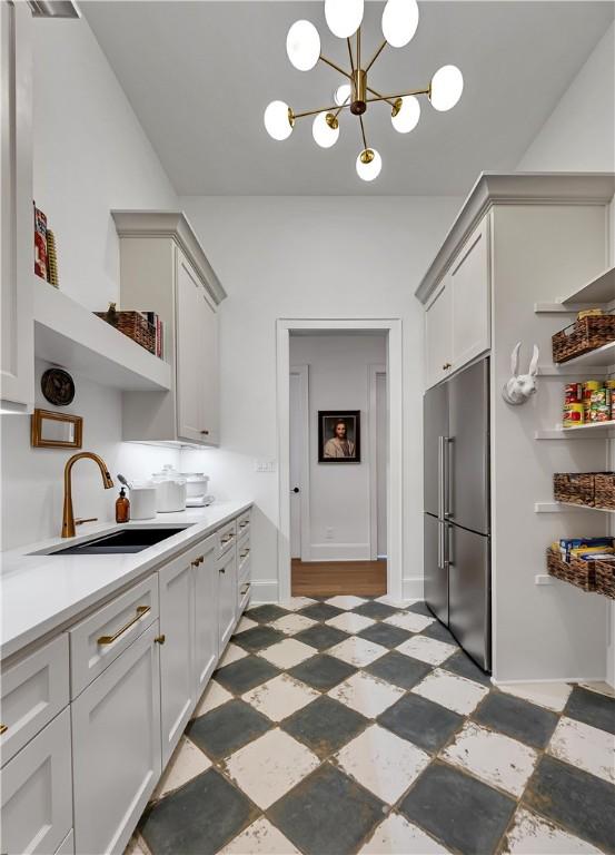 kitchen featuring stainless steel built in fridge, sink, and a notable chandelier