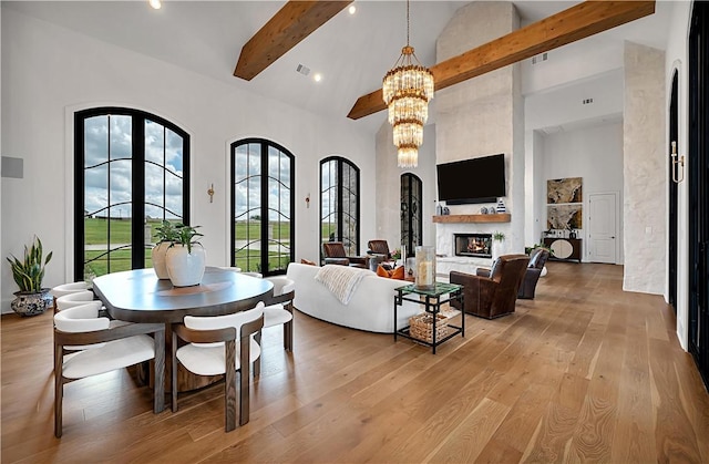 living room featuring beamed ceiling, a chandelier, high vaulted ceiling, and light wood-type flooring